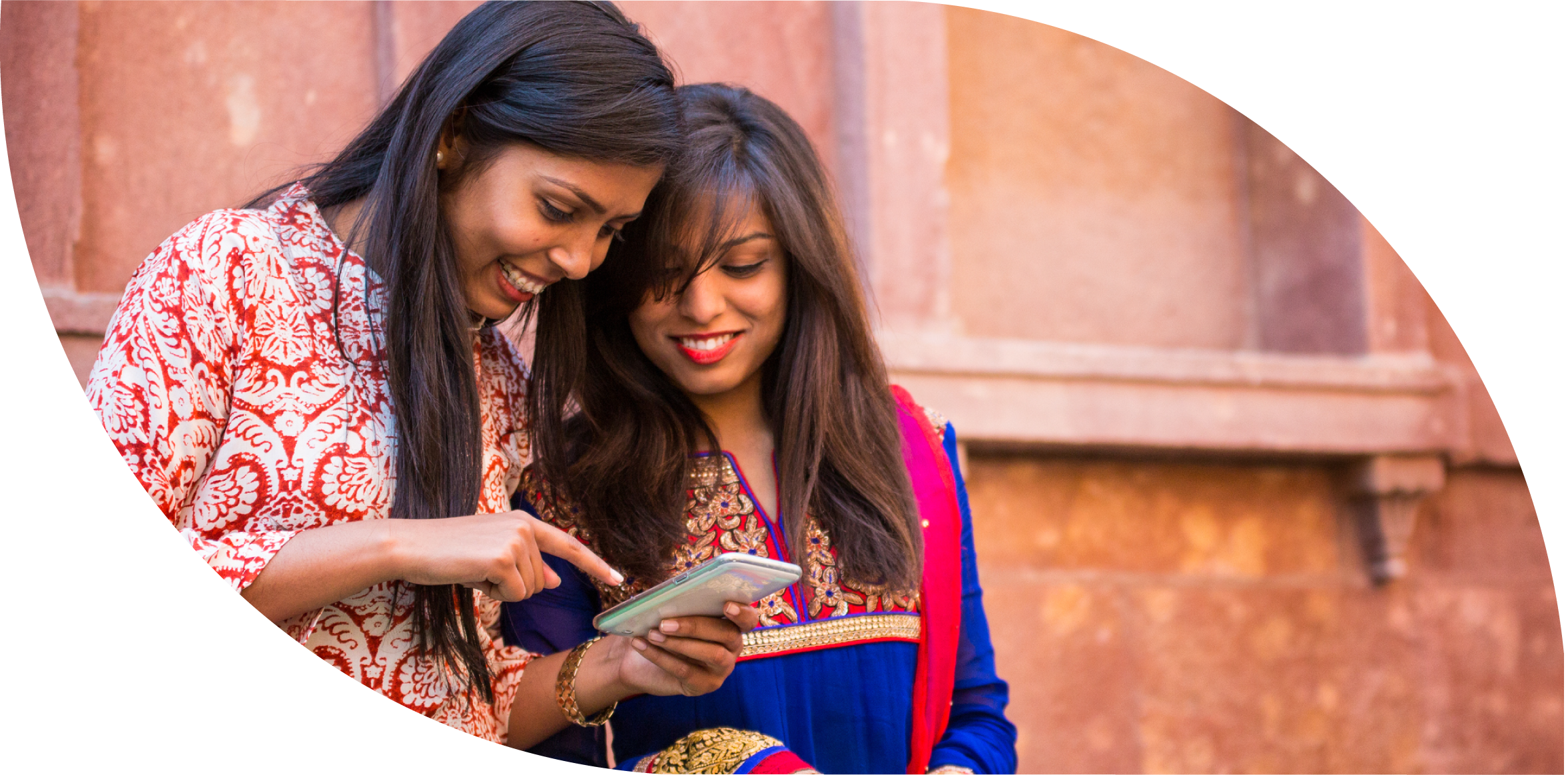 Two women are looking at a mobile phone.