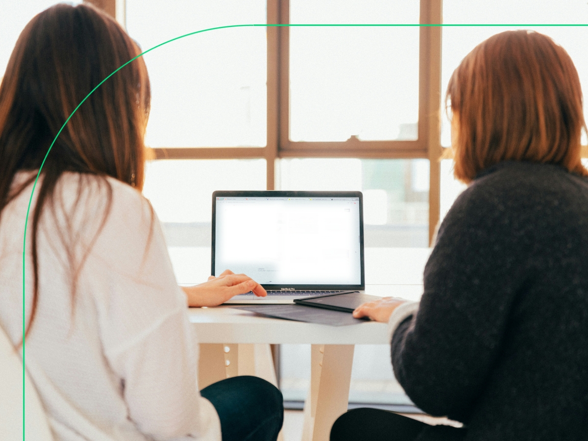 Two people sitting in the office and looking at a laptop screen, most likely discussing the difference between VAT output and VAT input in the UAE.