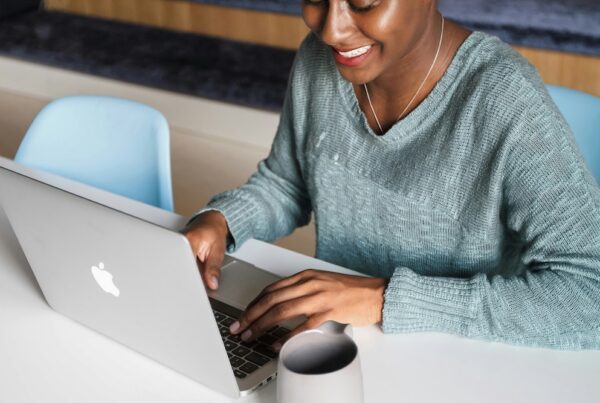 A payroll manager smiling at their laptop as she improves her payroll efficiency with NOW Money