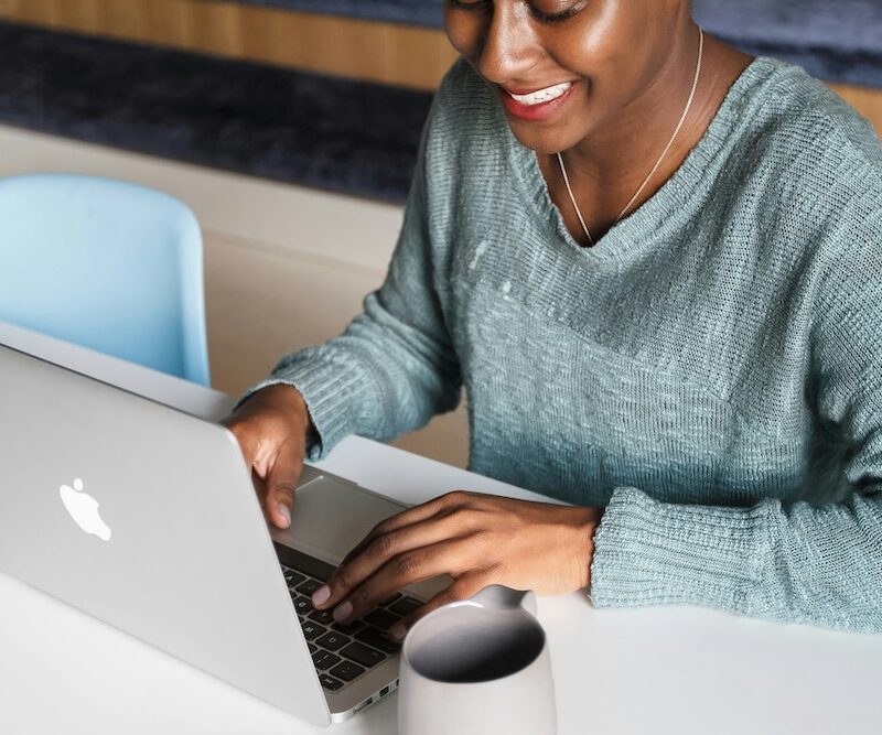 A payroll manager smiling at their laptop as she improves her payroll efficiency with NOW Money